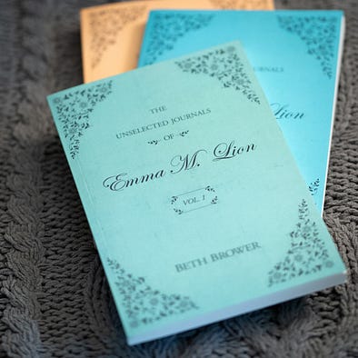 A stack of three volumes of The Unselected Journals of Emm M Lion by Beth Brower. The top book is light green with a flower pattern in the corners. A stack of three volumes of The Unselected Journals of Emm M Lion by Beth Brower. The top book is light green with a flower pattern in the corners.