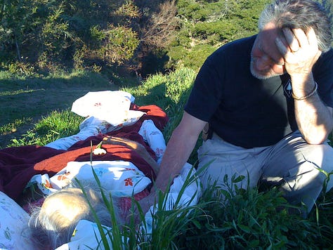 L to R: Back door to Bob's cabin, Toby and Bob. Bob was in hospice care and got to die at home, in his cabin, as he wished; Bob's cabin, which he built with Rosa, in the early 70s. He first bicycled to Big Sur in 1952, from the Bay Area. For love, of course; Bob "in state," in nature. Toby found some lupin and rosemary to wrap in his sheets; Susie wearing Bob's vest, in the cabin; Jay takes a look out at Partington Ridge with Bob; "Saint Bob." He would laugh at this one. He had little use for religion; Jon's drawing of Bob, in his bed, before we moved him outside. He wanted to be cremated, and since he lived so far from the road, we "wrapped" him in his bed linens, and carried him, like pallbearers without a coffin, up to the road where a fellow from the Mortuary met us; and Sula, Bob's executor, also drew Bob as he was in bed. This looks more like Bob when he was alive... he was a big, strong, guy!