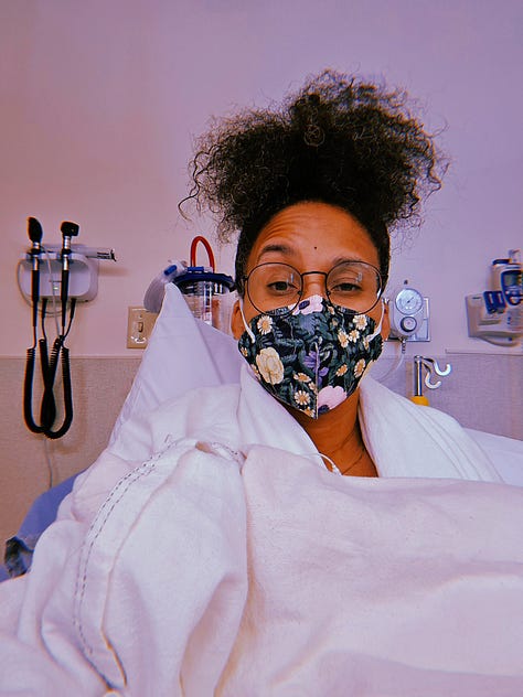 Images for Dr. Cadet in the ER from her braced left thumb adorned with pearls resting on heating packs. Her wrist with a yellow falls risk band, white medical ID band, red allergy band. Blue sheets, white pillow and cream heated blankets on a gurney and covering her like a burrito as she wears a floral mask in her ER room.
