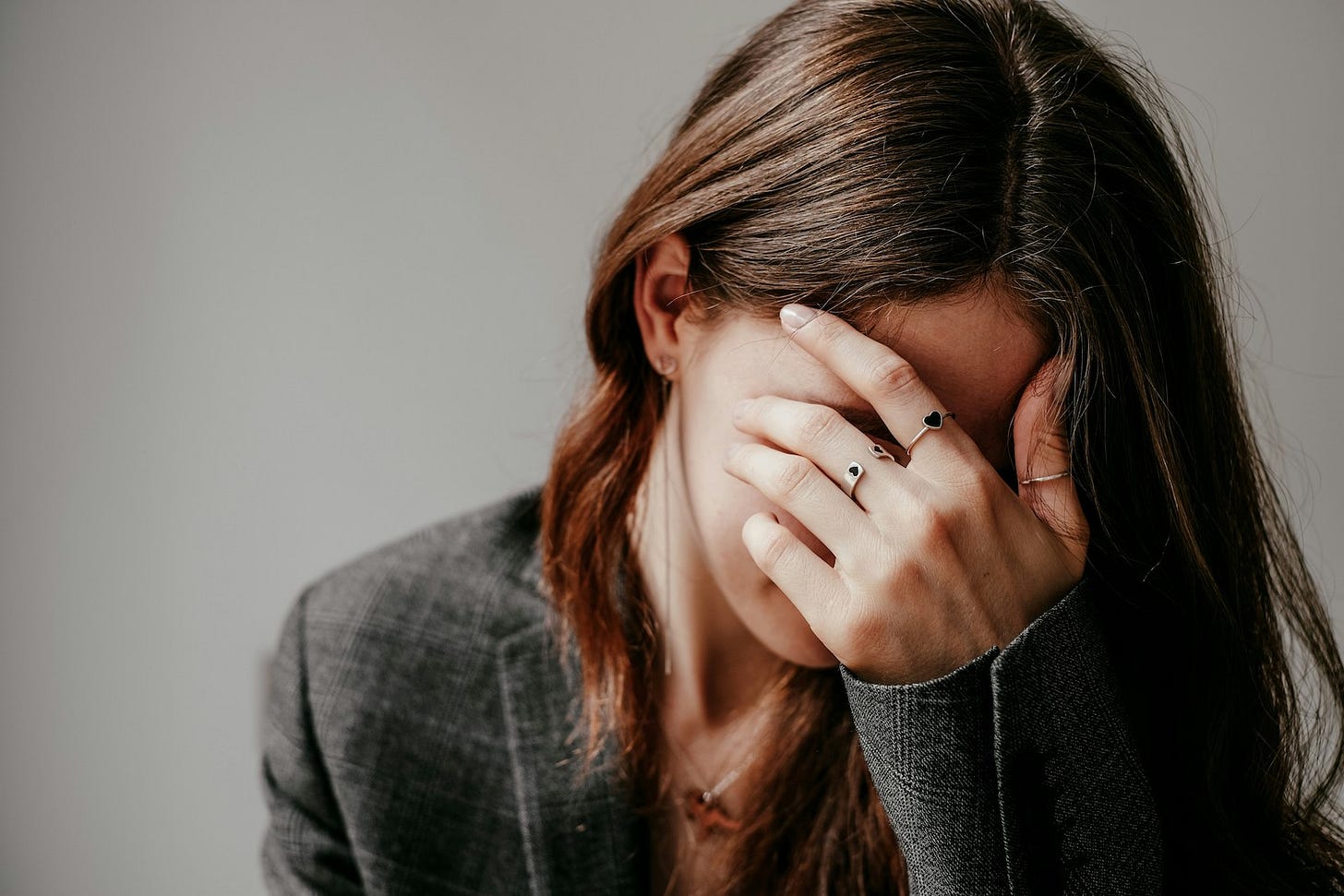 Young woman, long brown hair, covers her face in distress. Young woman, long brown hair, covers her face in distress.