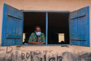 A man wearing a mask looks out from a window in Nigeria. The researchers surveyed people in 27 countries across North America, South America, Europe, Asia and Africa.