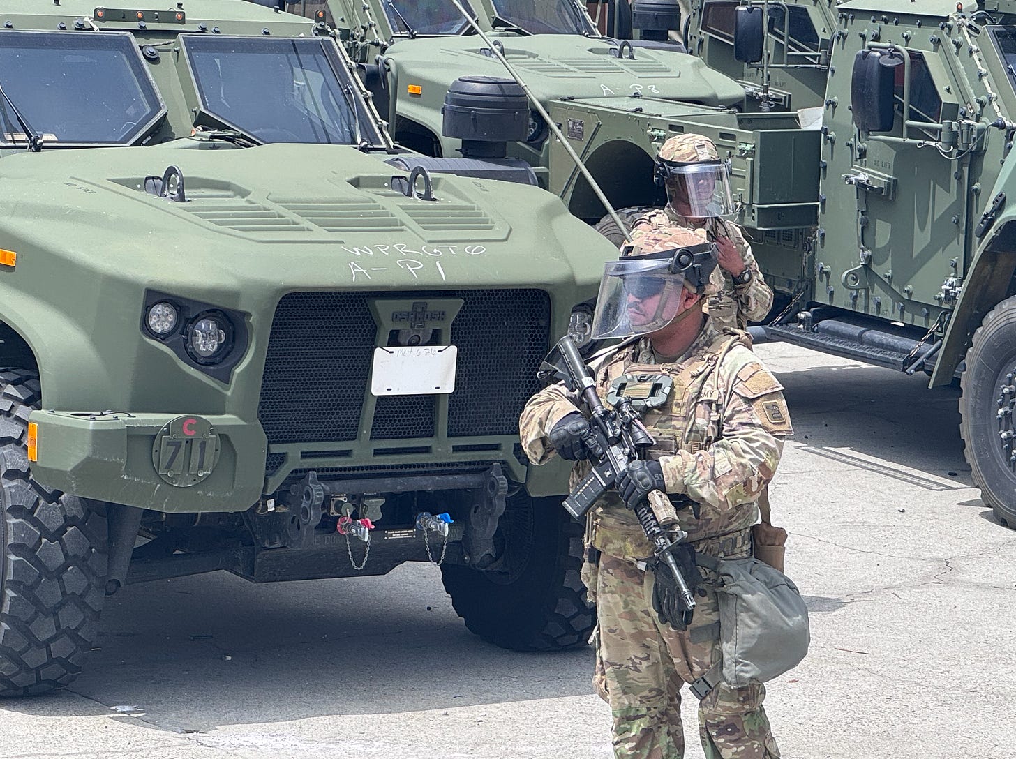 National guard with gun in front of armored vehicle National guard with gun in front of armored vehicle