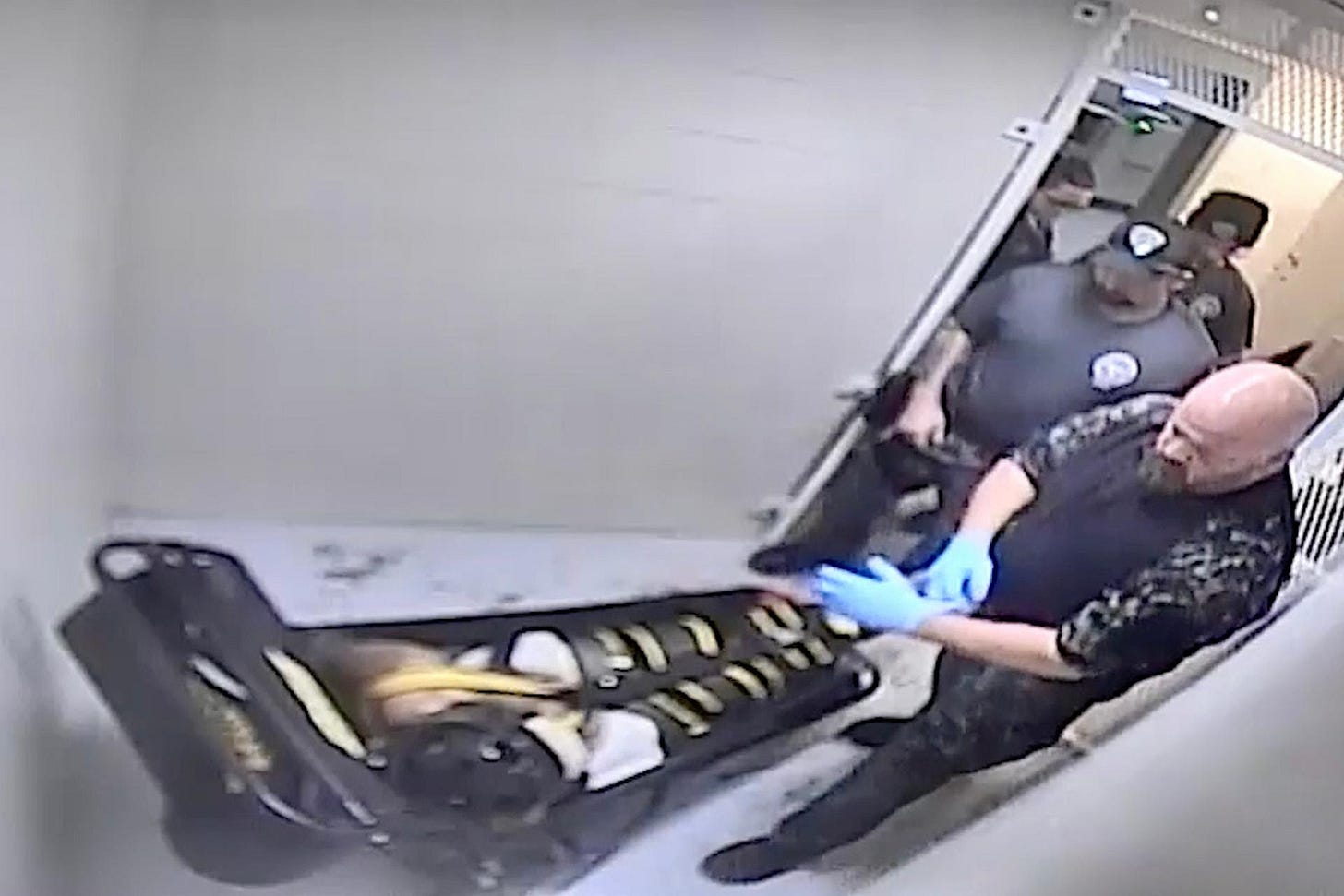 In this image from Dec. 2023 surveillance video provided by Jefferson City Correctional Center, jailers examine Othel Moore Jr., who according to an autopsy asphyxiated in the WRAP restraint. (Jefferson City Correctional Center via AP)