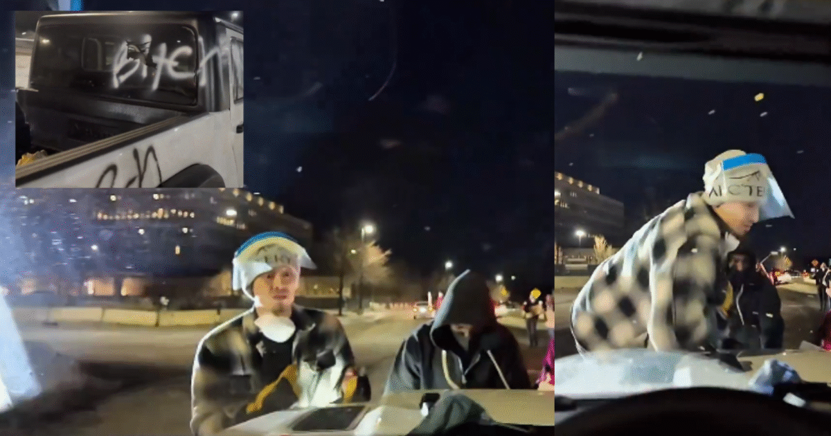 Young individuals interacting near a vehicle at night, with graffiti visible on the car's rear window, capturing a moment of urban activity.