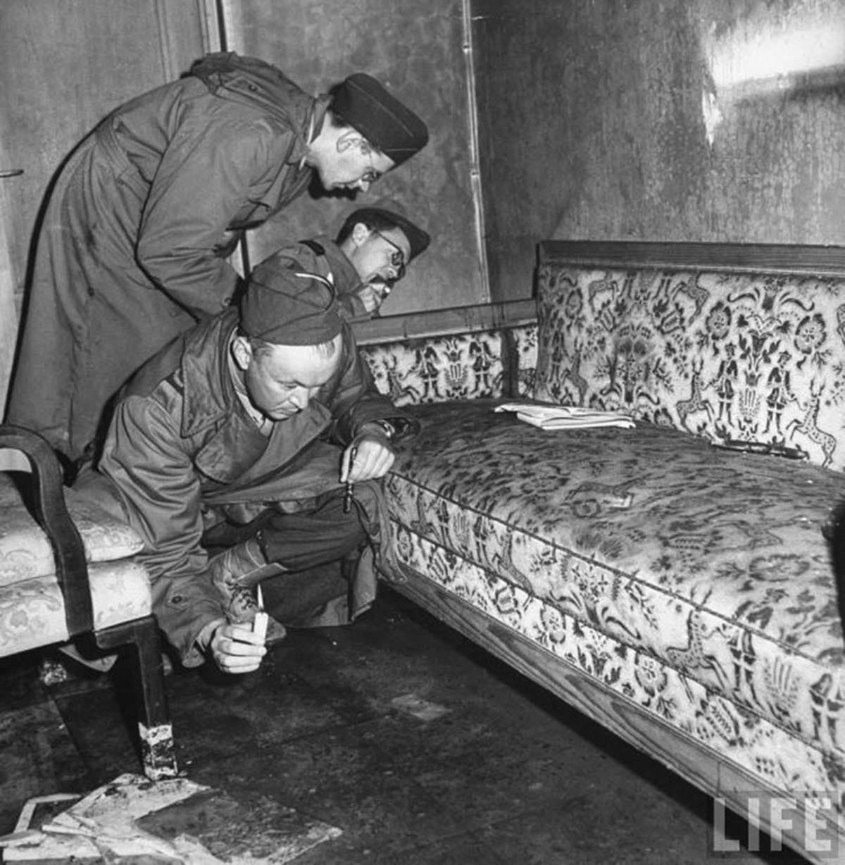 American soldiers inspect the sofa believed to be where Adolf Hitler and Eva Braun committed suicide, noting visible bloodstains on the carpet. American soldiers inspect the sofa believed to be where Adolf Hitler and Eva Braun committed suicide, noting visible bloodstains on the carpet.