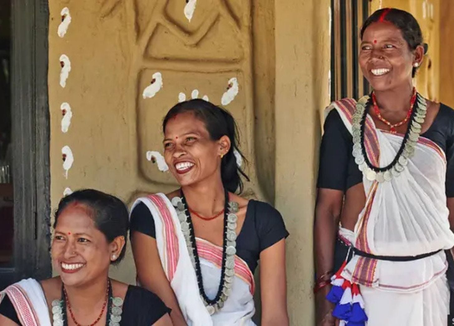 Women from a community-run homestay program in Nepal standing outside a village home, reflecting how locally hosted stays create familiarity and trust for visitors.