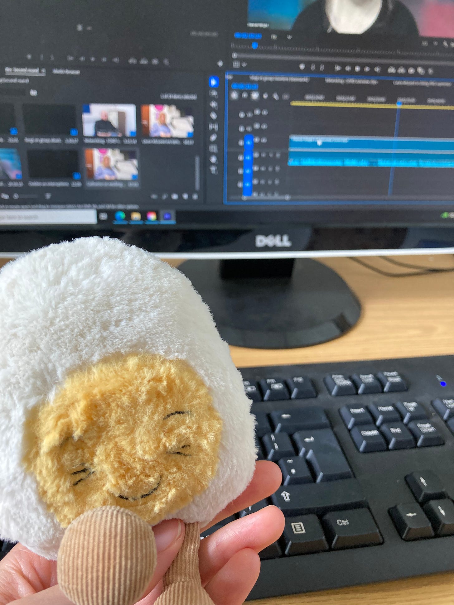Dippy the soft toy egg in front of a keyboard and computer monitor with video editing software open