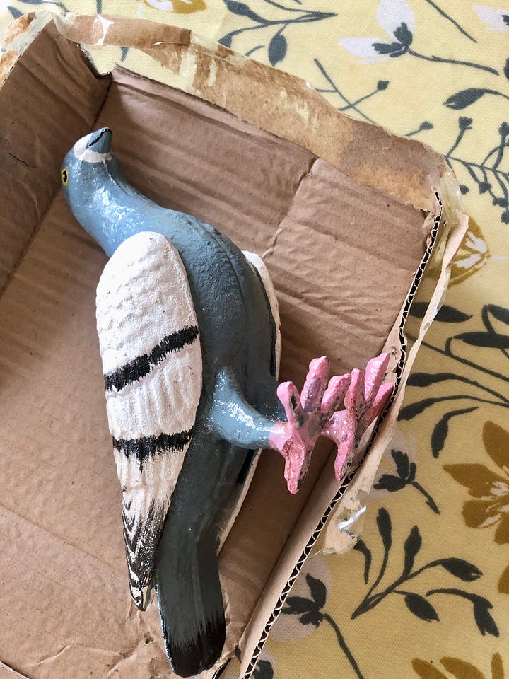 Photos showing a cast iron figure pigeon coming out of a cardboard box