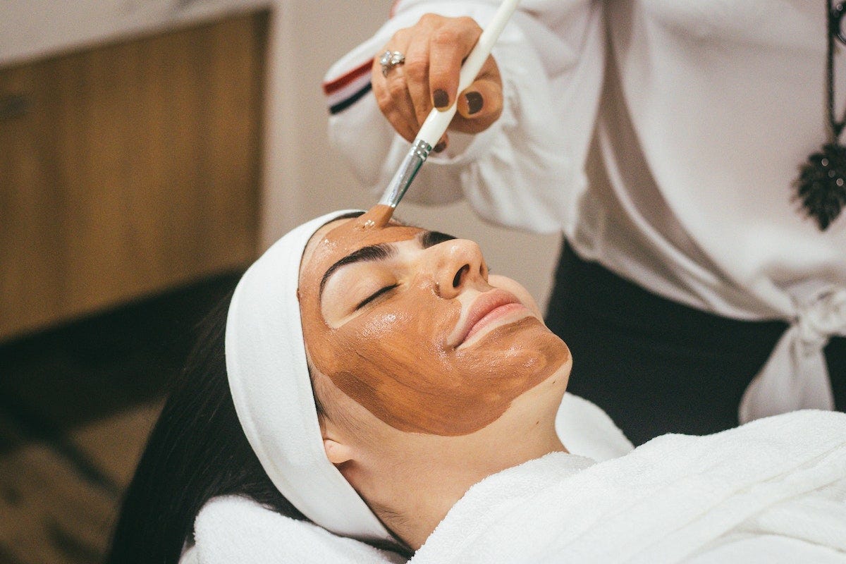 woman getting facial with professional skincare line face mask