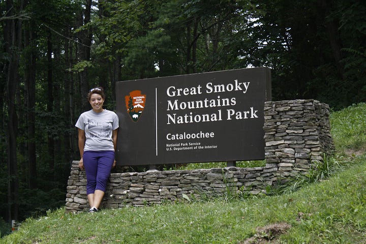 Two images of Nicole in Smoky Mountain National Park. In the first, she poses in front of the park sign in Cataloochee (Eastern Tennessee). In the second image, we see the back of Nicole's hiking pack as she faces away toward a wooden bridge crossing a creek.