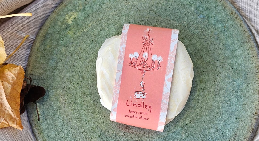 A green plate with a soft cheese with a pink wrapper on it A green plate with a soft cheese with a pink wrapper on it