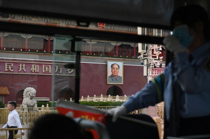 A security official walks near a portrait of Mao Zedong on Tiananmen Gate, viewed from a bus with a conductor in the foreground. A security official walks near a portrait of Mao Zedong on Tiananmen Gate, viewed from a bus with a conductor in the foreground.