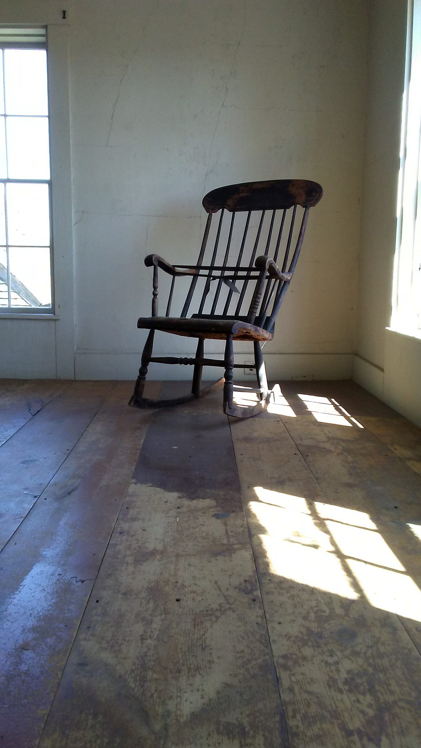 Bare interior room of the Olson House with worn wooden floorboards and a window Bare interior room of the Olson House with worn wooden floorboards and a window