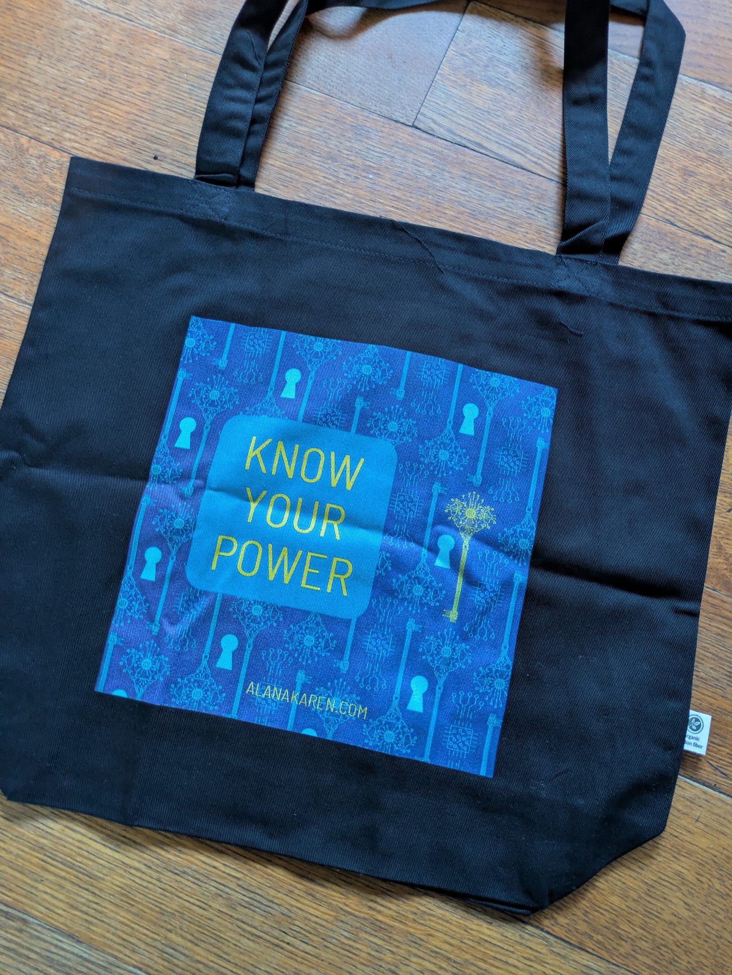 Black tote bag. Know your power message. Pattern: blue with keyholes and yellow key.