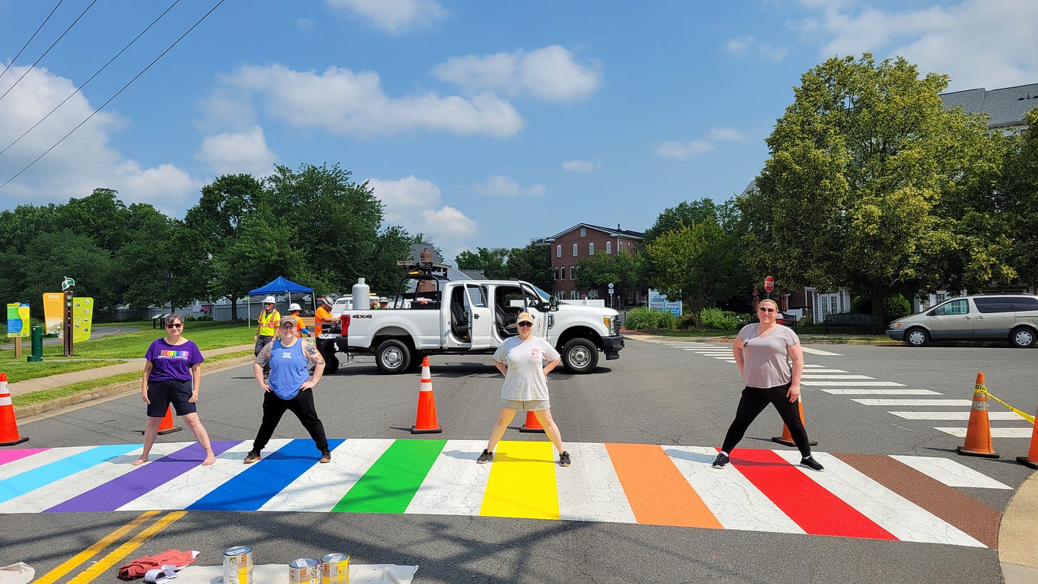 A group of individuals poses on a colorful rainbow crosswalk in Leesburg, VA,