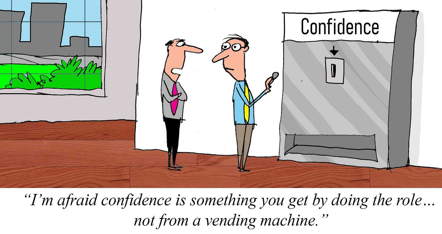 Cartoon of an employee standing beside a vending machine labeled “Confidence,” holding a coin as if trying to buy some, while a manager explains that confidence comes from doing the job, not from a vending machine.
