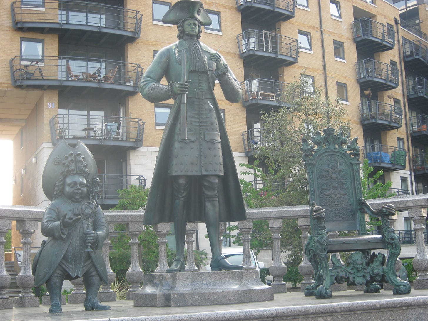A deeply weird statue of Peter the Great - hugely tall, but with a tiny head - flanked by a dwarf in a tall hat and a bronze throne. It stands in front of a block of dockland flats