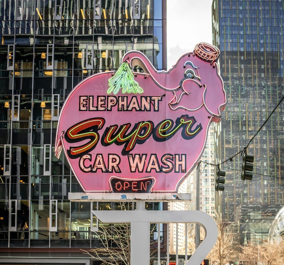 a pink elephant super car wash sign on a city street