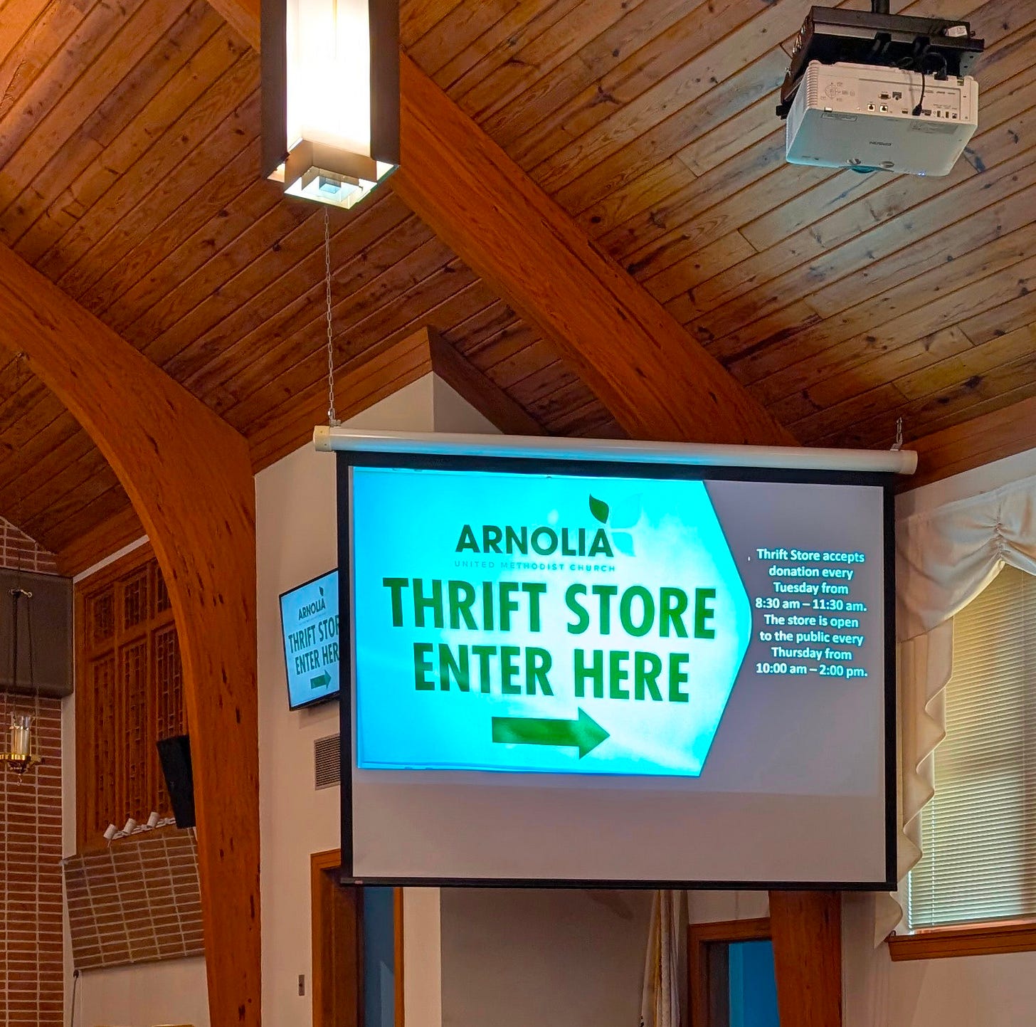 A photo of the projector screen down with the projector mounted on a pole from the ceiling.