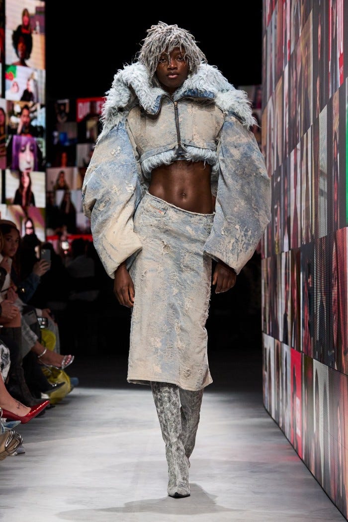 A model in a white over-sized jacket, skirt and boots 