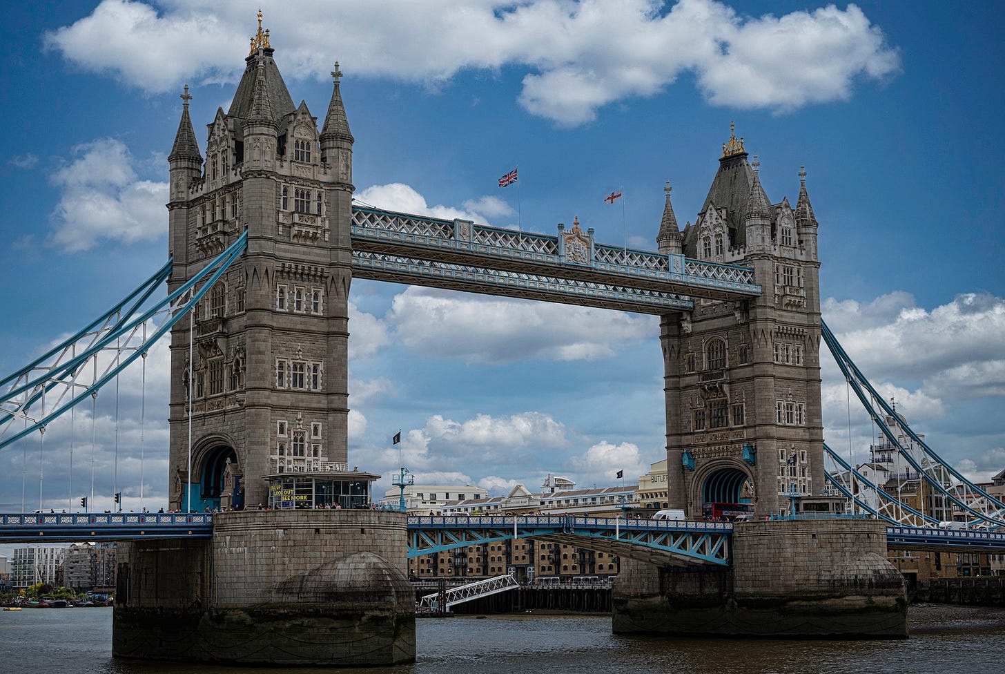 Tower Bridge spans the River Thames in London, featuring its iconic twin towers against a backdrop of blue skies and fluffy clouds. Tower Bridge spans the River Thames in London, featuring its iconic twin towers against a backdrop of blue skies and fluffy clouds.