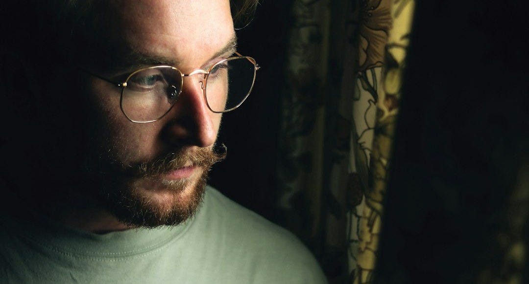 man wearing eyeglasses looking outside curtains man wearing eyeglasses looking outside curtains