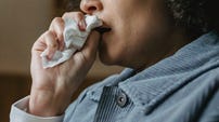 A person crying into a tissue. A person crying into a tissue.