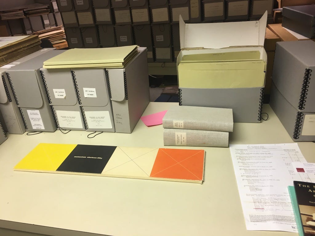 gray folder boxes on a library table with a book laid out to view