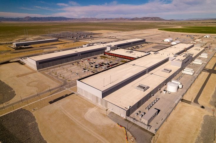 This may contain: an aerial view of a large industrial building in the middle of nowhere with mountains in the background