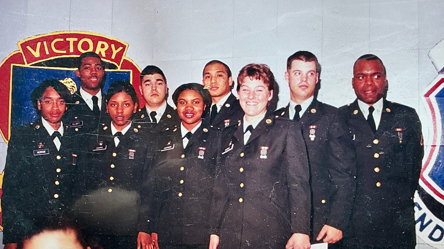 Several female and male soldiers in Class A uniforms posing for a picture on graduation day