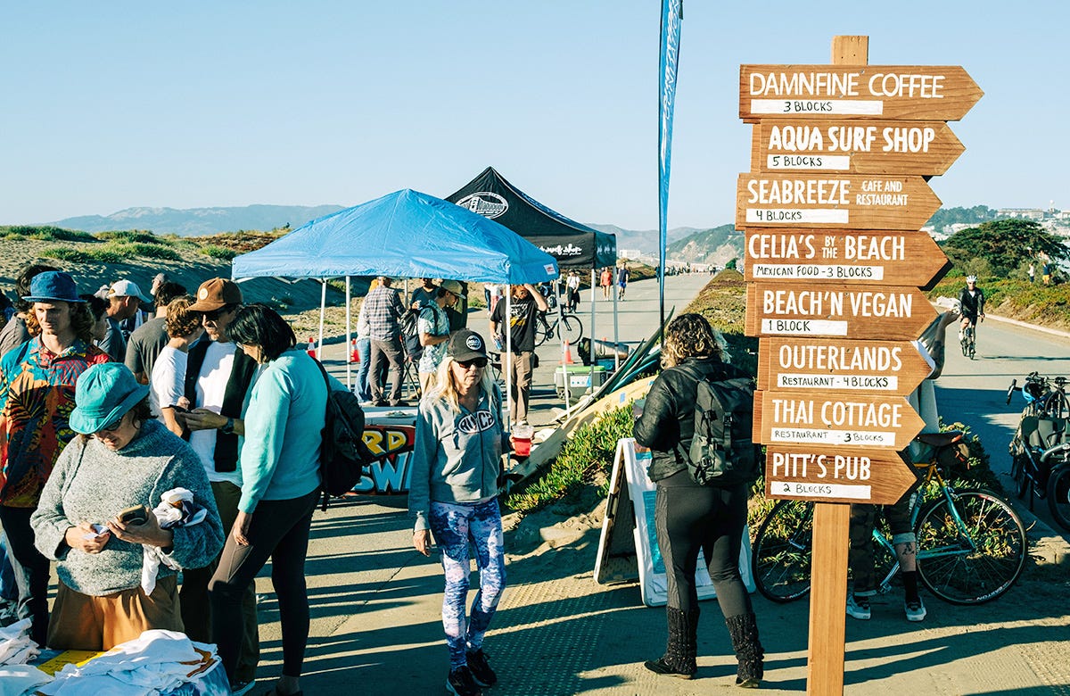 People hanging out on San Francisco's Great Highway with a wayfinding sign directing them to nearby businesses in the foreground.