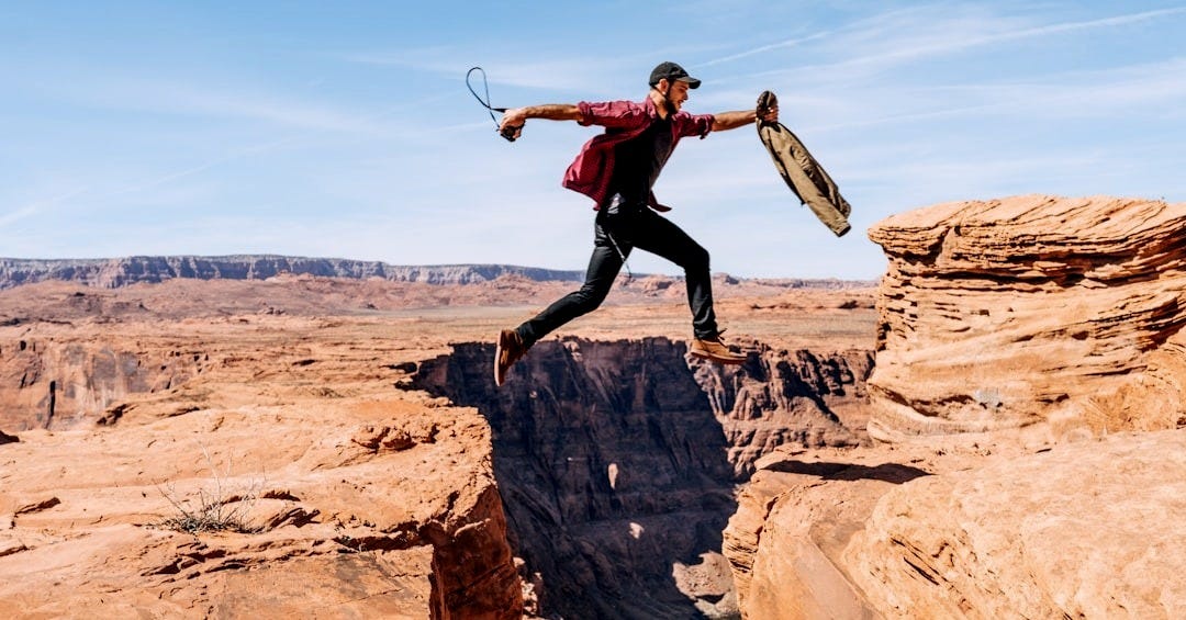 man jumping on rock formation man jumping on rock formation
