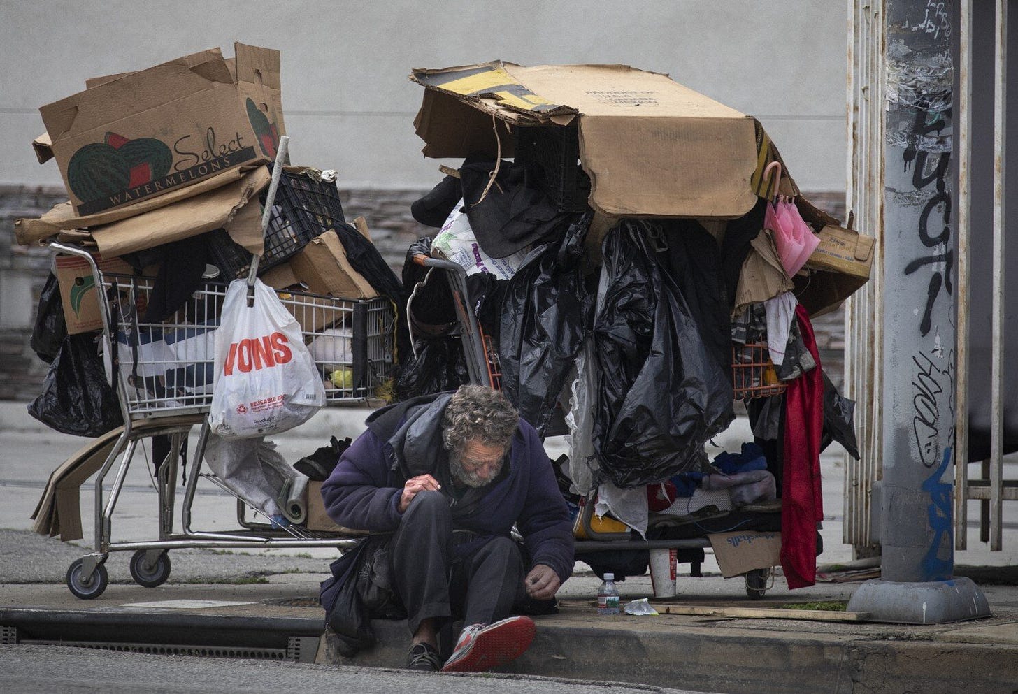 Homeless man on a curb with all of his possessions in two shopping carts. Homeless man on a curb with all of his possessions in two shopping carts.