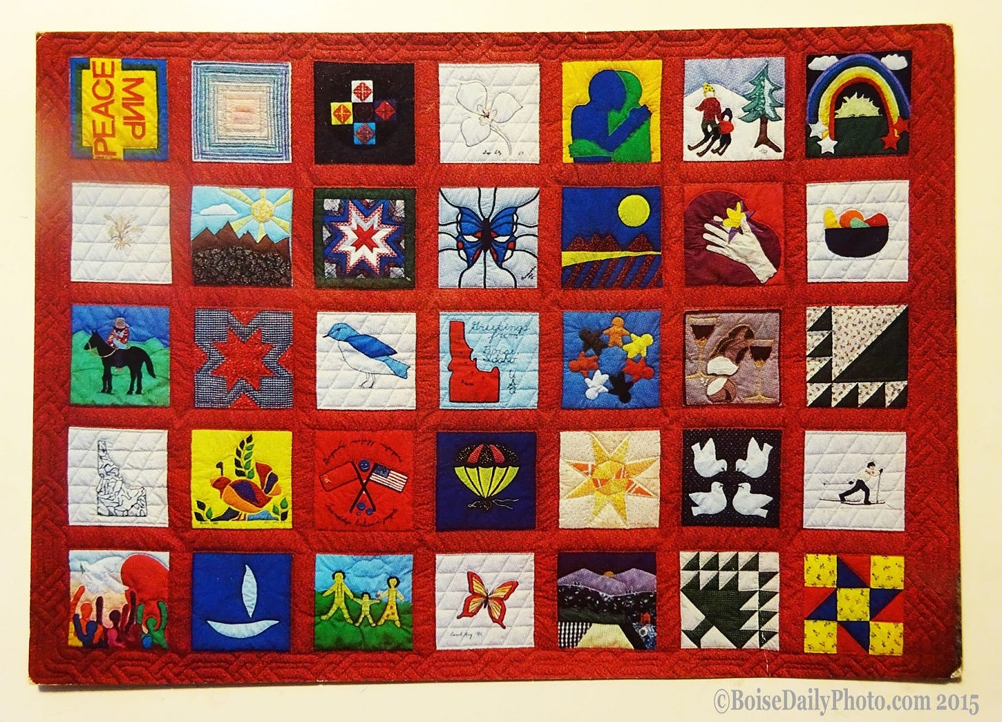  A vintage postcard (1982) featuring the first Boise Peace Quilt. This was a Cold War quilt. From the back of the card, "A gesture of friendship to the ordinary people of the Soviet Union from 25 Idahoans." The Boise Peace Quilt project still makes quilts today.    Postcard photo credit: Lenoard Nolt 