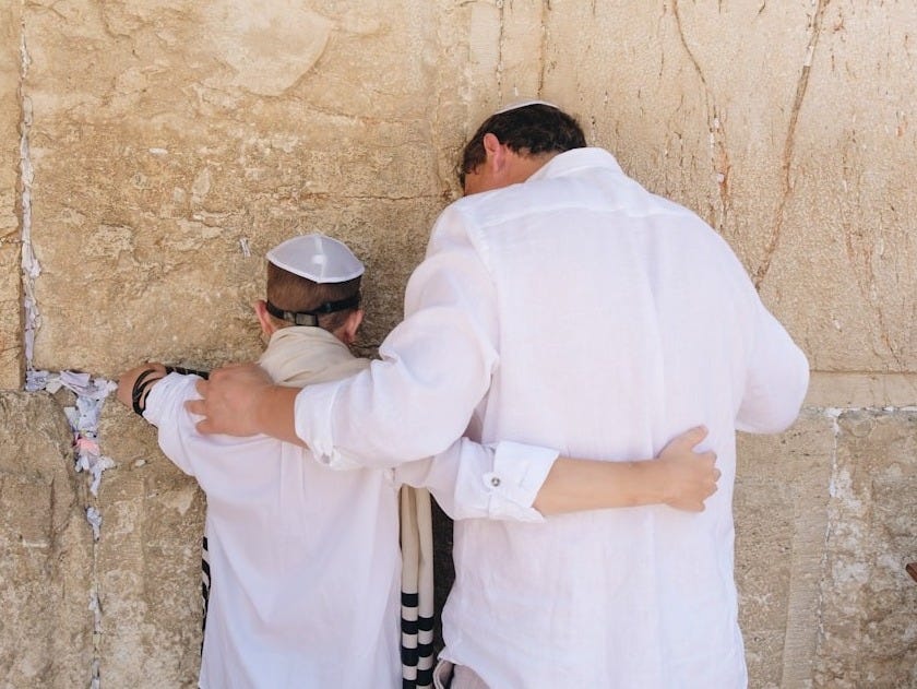 two men in white top standing beside wall