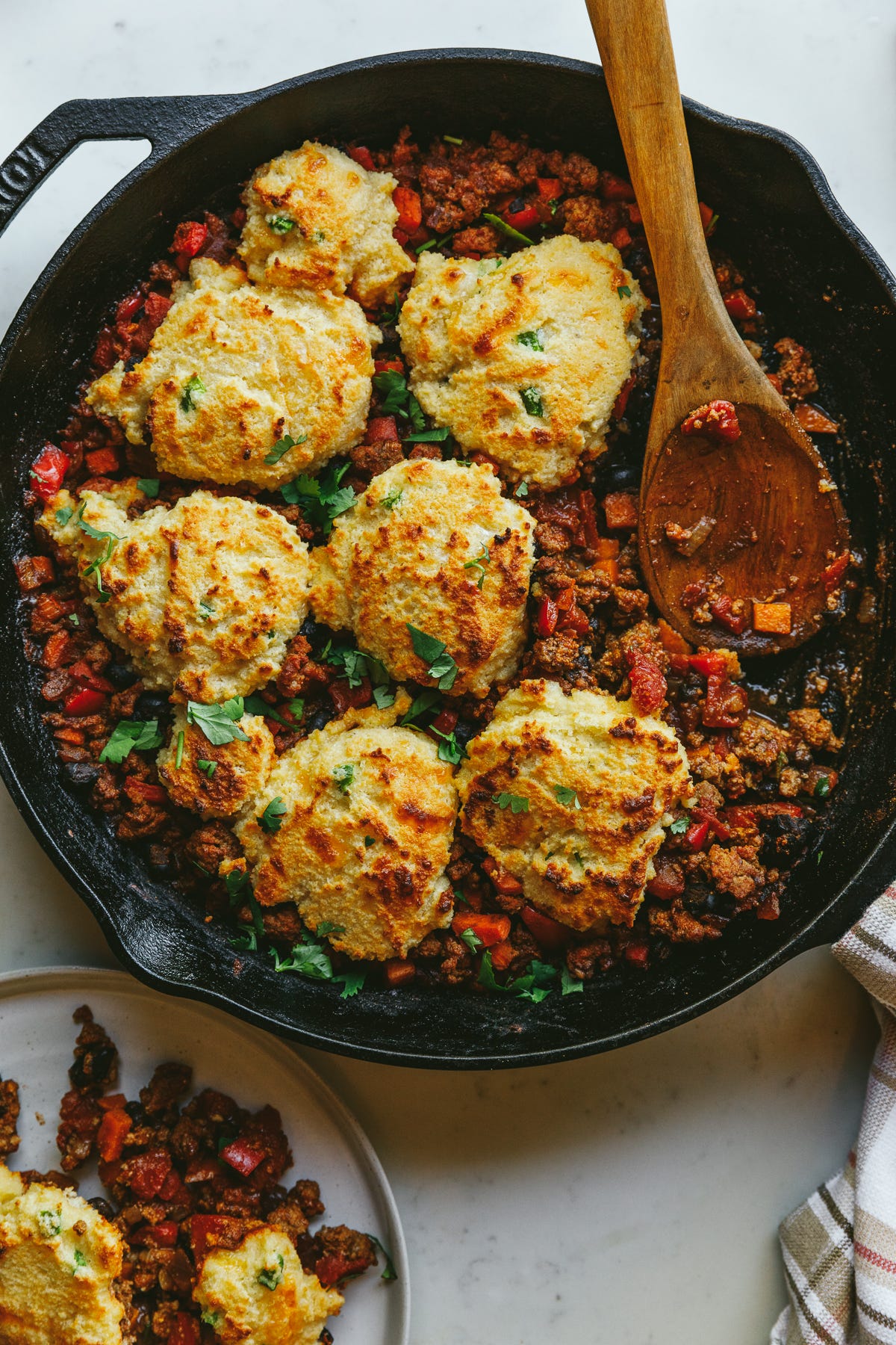 Chili cornbread casserole in a black skillet with a spoon.