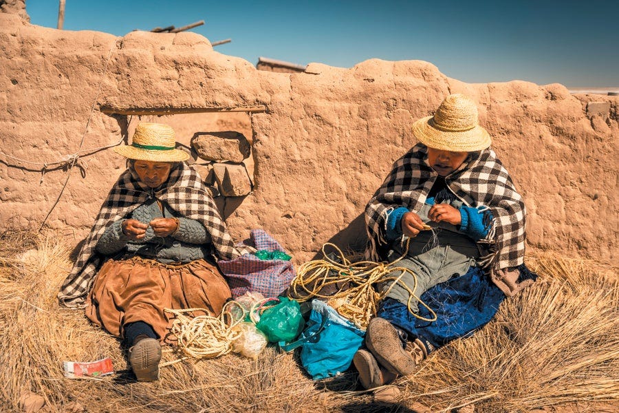 Two Uru people of the Bolivian Altiplano sitting outside in traditional clothing