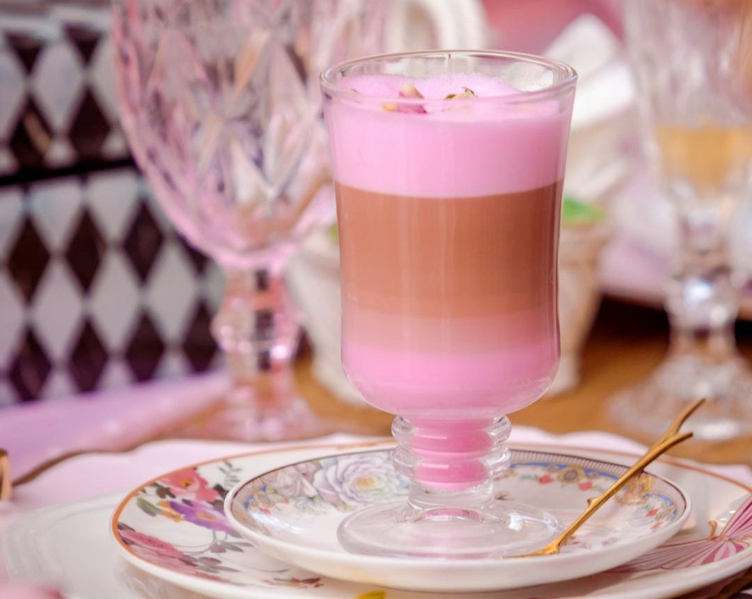 a pink drink on a plate on a table