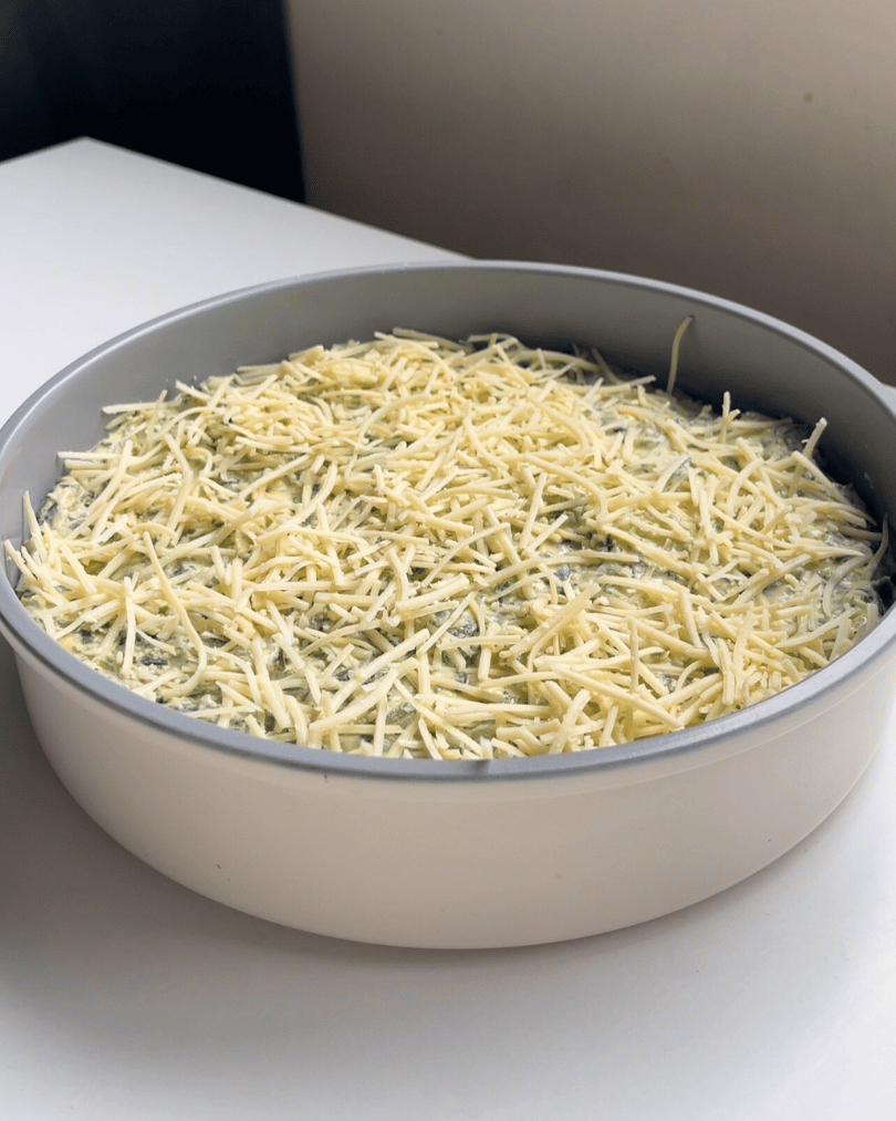grey pan with dip inside and vegan parmesan on top, ready for the oven