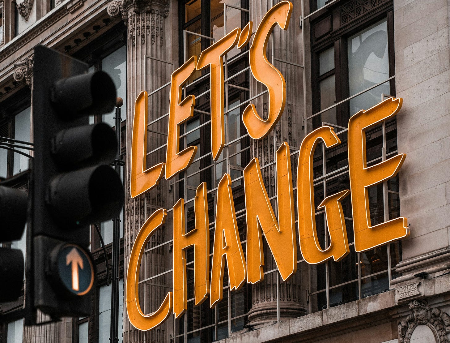 a woman walking past a building with a sign that says let's change a woman walking past a building with a sign that says let's change