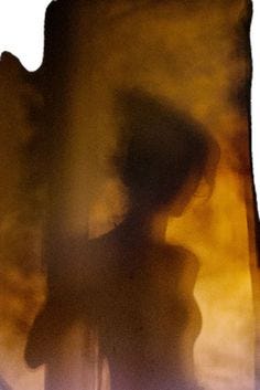 This may contain: a blurry image of a woman standing in front of a window with the sun coming through
