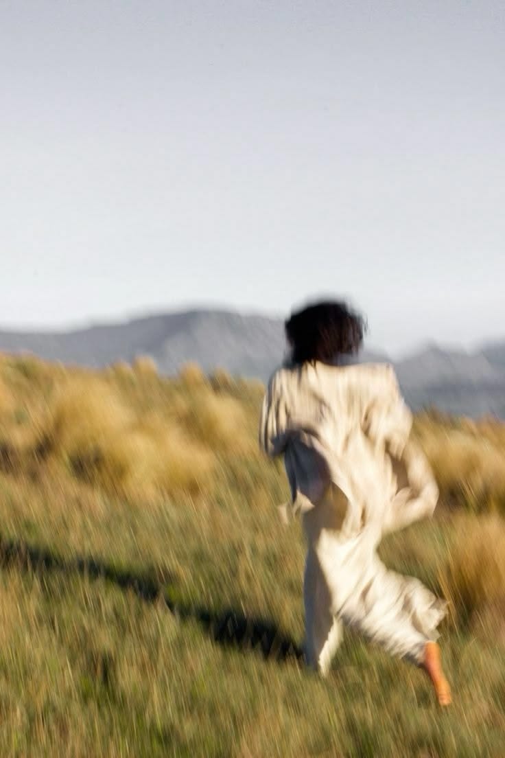 This may contain: a person running in the grass with a frisbee on their hand and an animal behind them