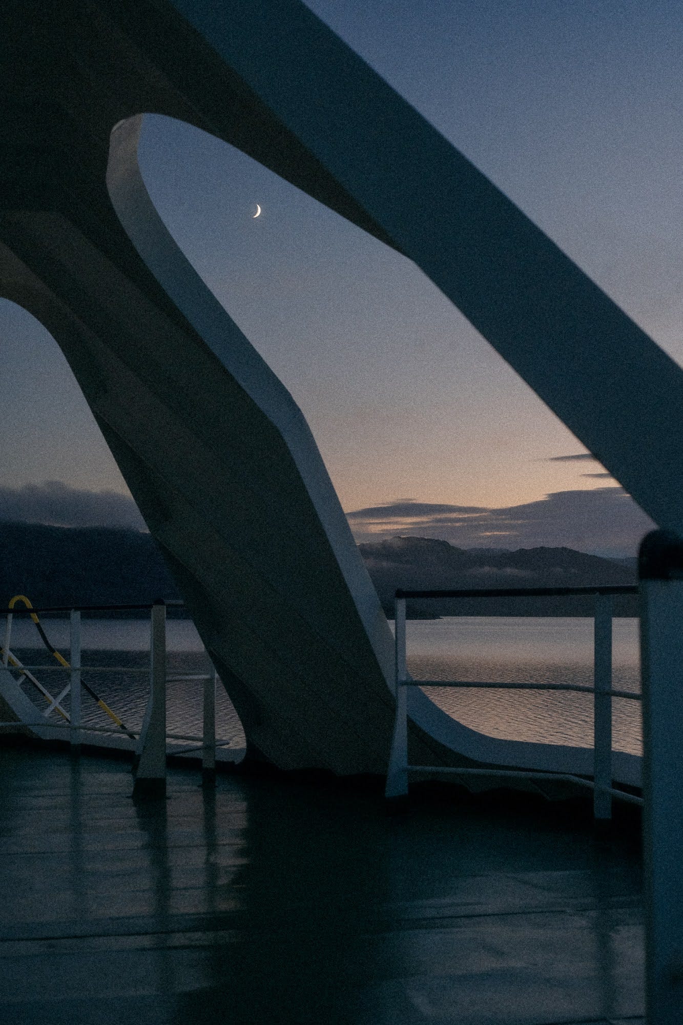 Arches on the ferry frame a crescent moon in the early morning.