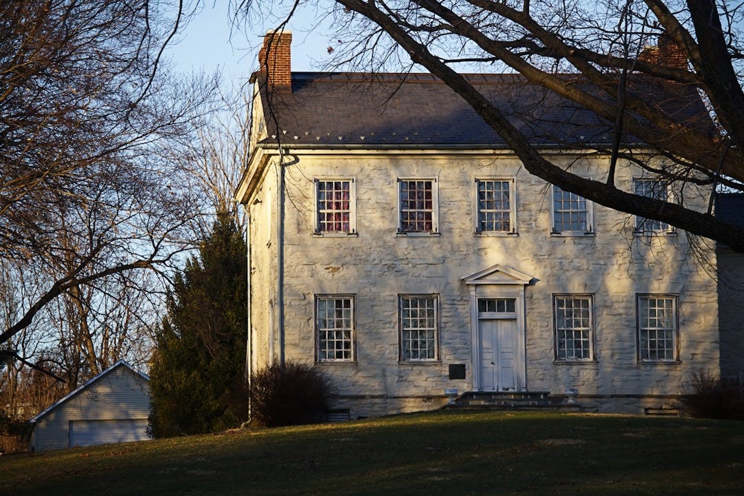 A vintage house stands on a grassy hill.