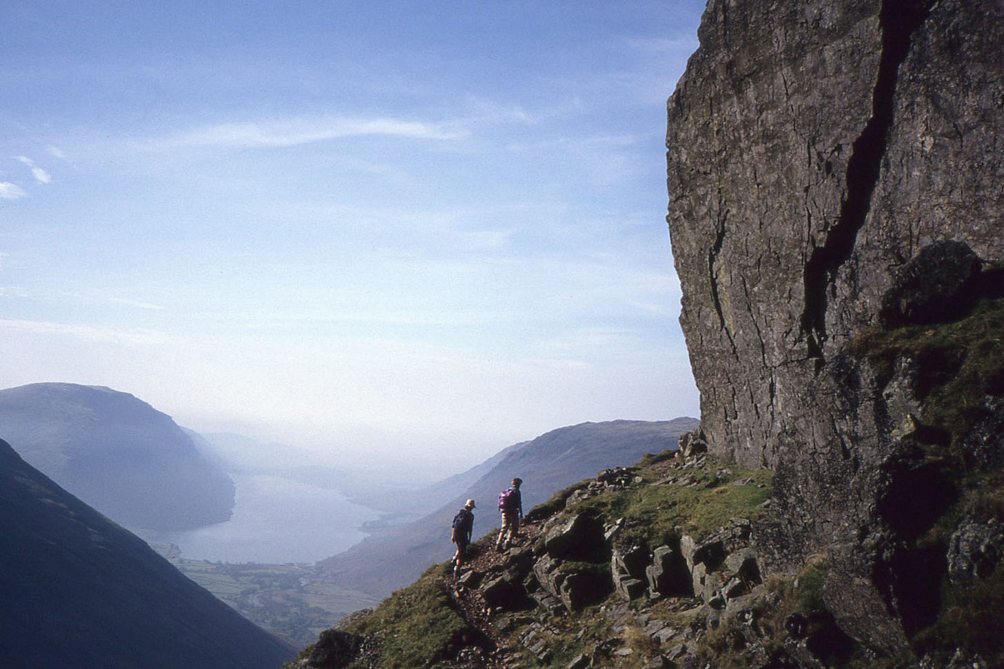 two walkers below a crag