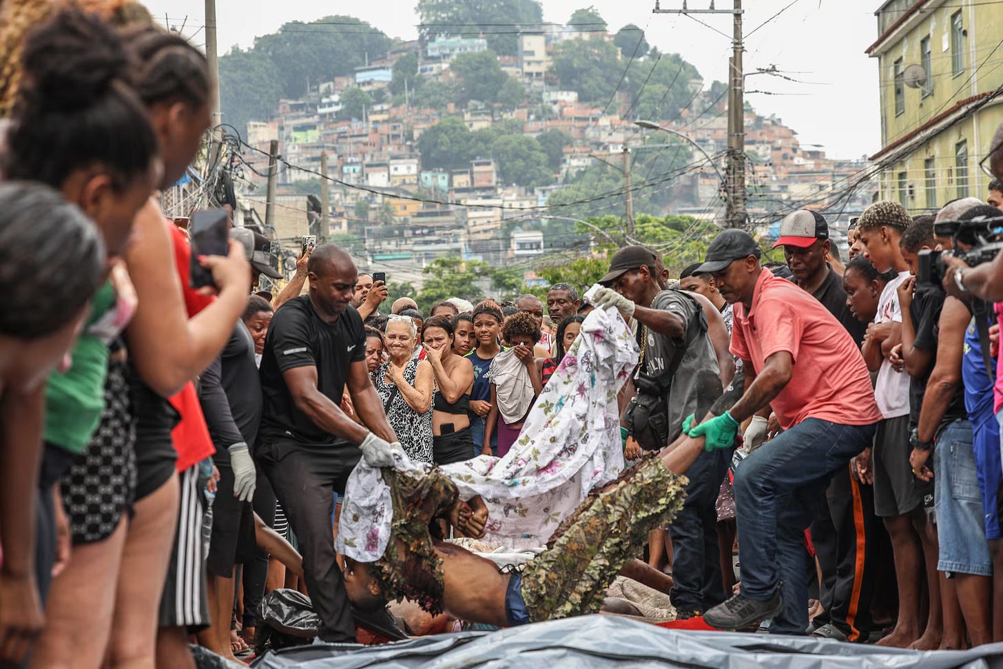 People arrange lifeless bodies in a street in the Penha favela (Credits: André Coelho/EFE)
