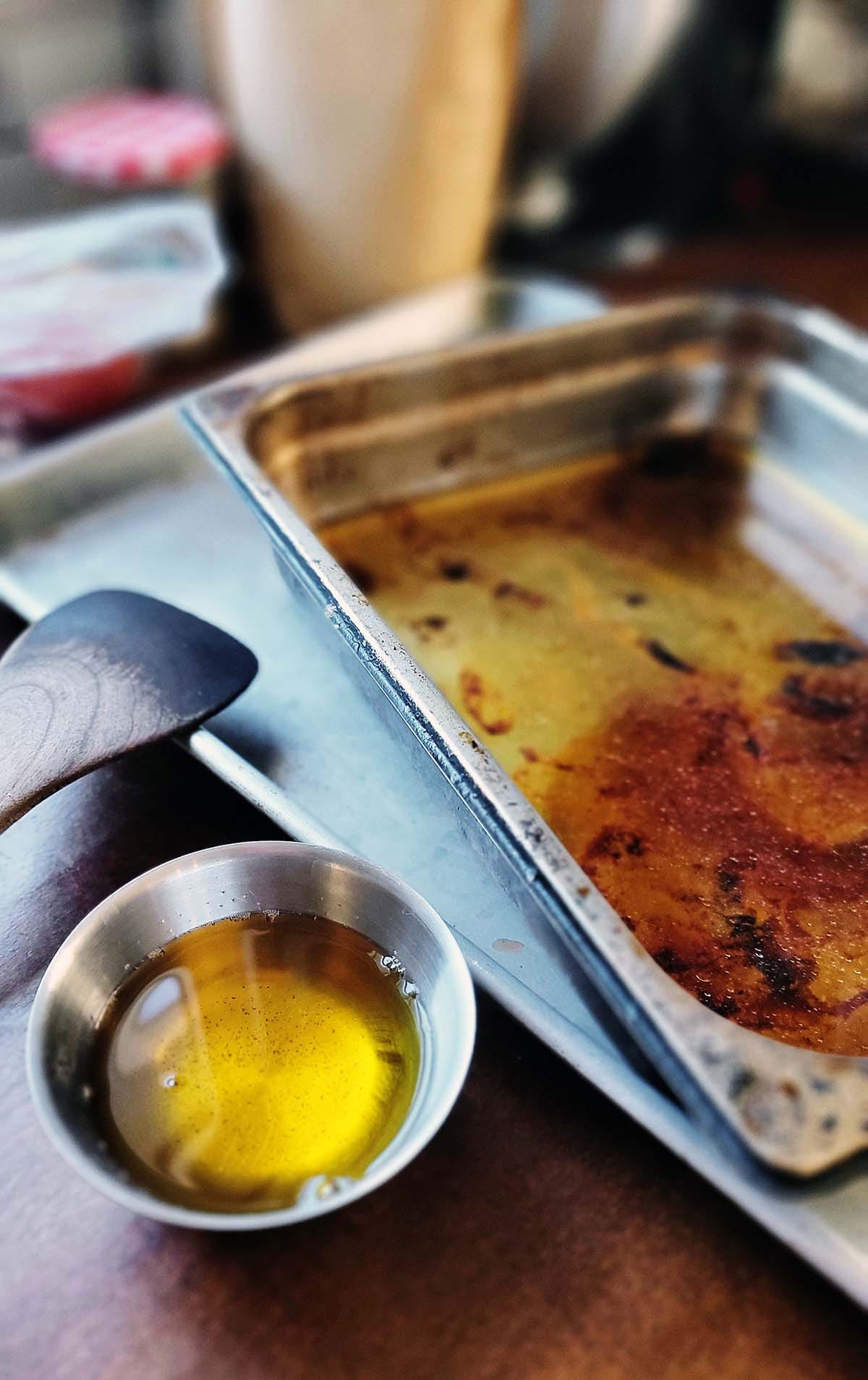 A small bowl of duck fat, and a pan of fond leftover from roasting bones. 