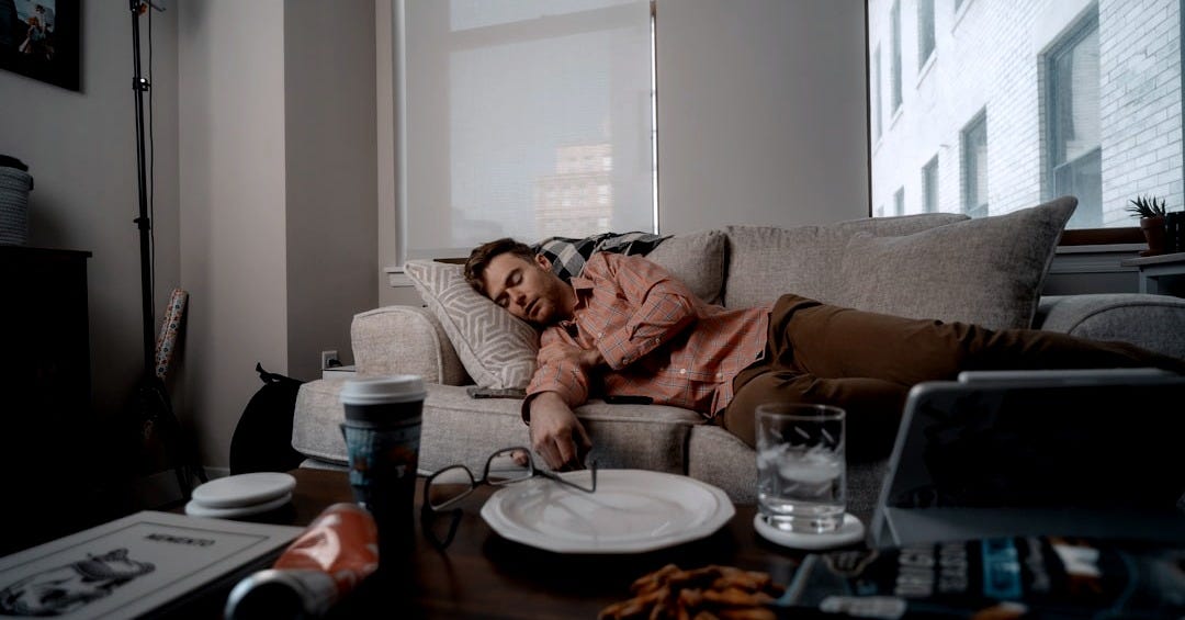 a woman laying on a couch with a plate of food