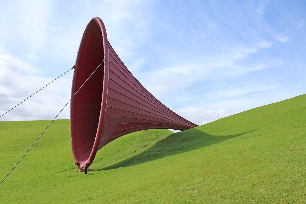 A large red funnel on a green hillside beneath a clear blue sky
