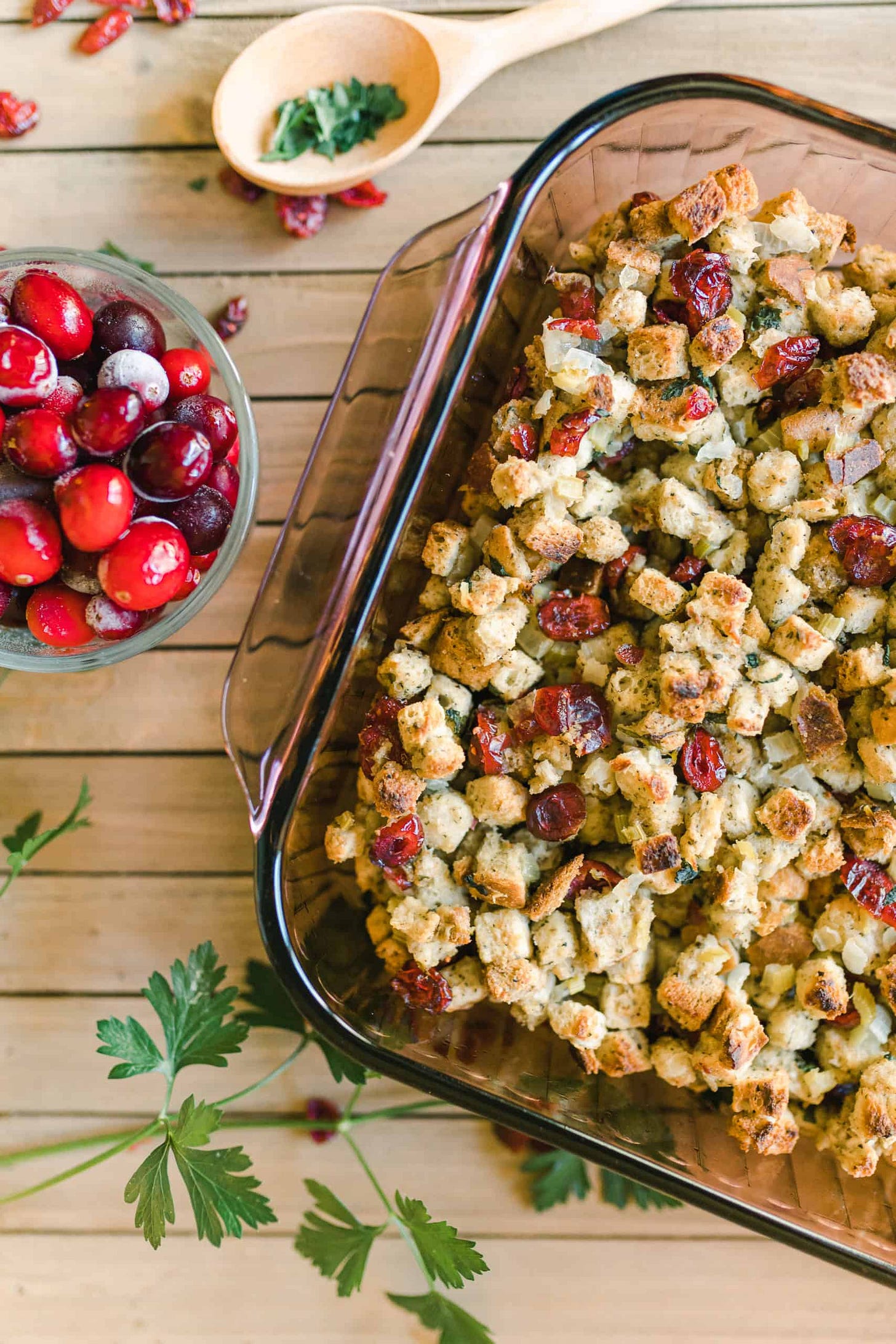Cranberry Traditional Stuffing Recipe in a baking pan with a dish of frozen cranberries.